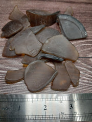 Brown frosted sea glass pieces placed next to a ruler to show size dimensions.