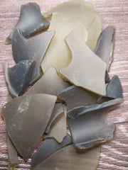 A pile of frosted olive green seaglass pieces on a table