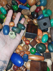 A vibrant mixture of wooden crafting beads in various colors, shapes, and textures, ranging from 1/2 inch to 1 1/2 inches, ideal for DIY and art projects