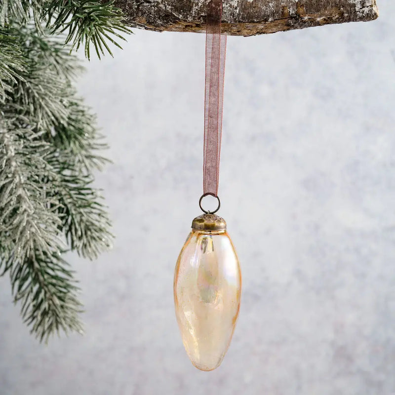 2" Champagne Luster Conical Glass Christmas Ornament with a bronze cap and pink organza ribbon, hanging from a branch with a frosted pine branch in the background.