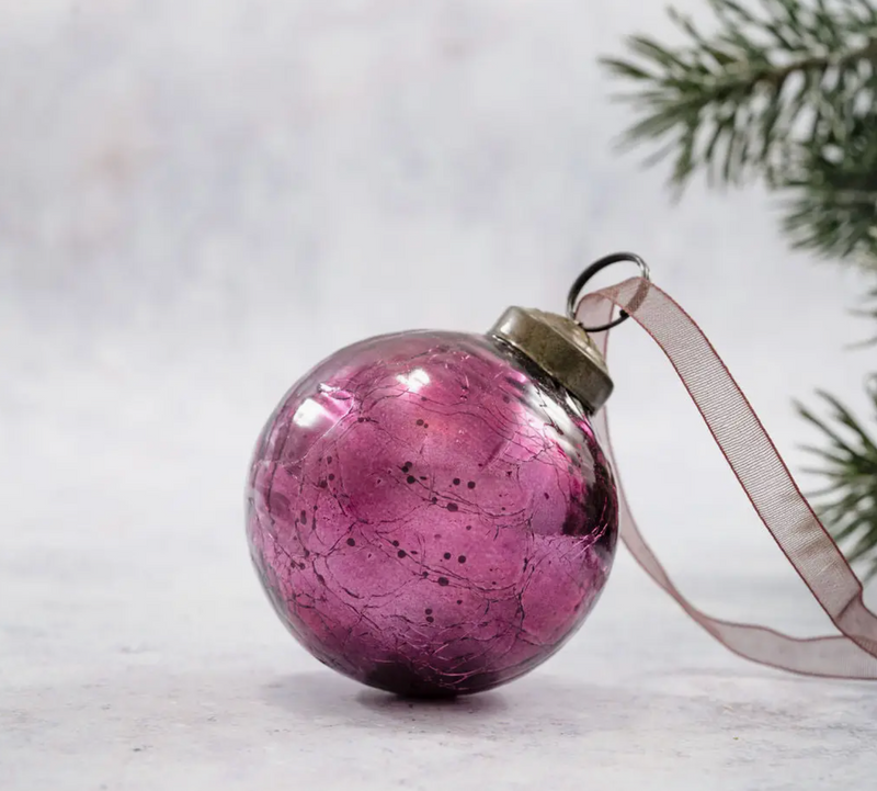 2" Mulberry Crackle Glass Christmas Bauble with a hand-blown crackle effect, bronze cap, and coordinating organza ribbon, lying on its side near frosted greenery.