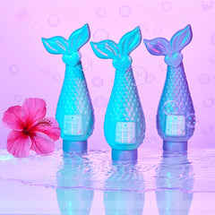 Three blue mermaid tail bottles with a pink flower on a purple background