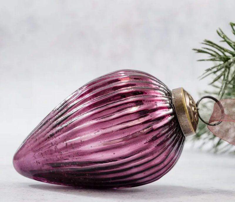 3" Mulberry Glass Pinecone Ornament with ribbed glass design and ornate bronze cap, lying on its side with a frosted pine branch in the background.