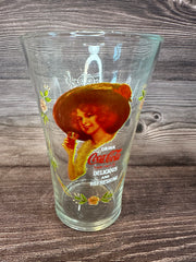 Vintage Coca Cola Magnificent Ladies Collector Series 1 Glasses featuring vibrant images of women in classic Coca-Cola advertising on a wooden surface.