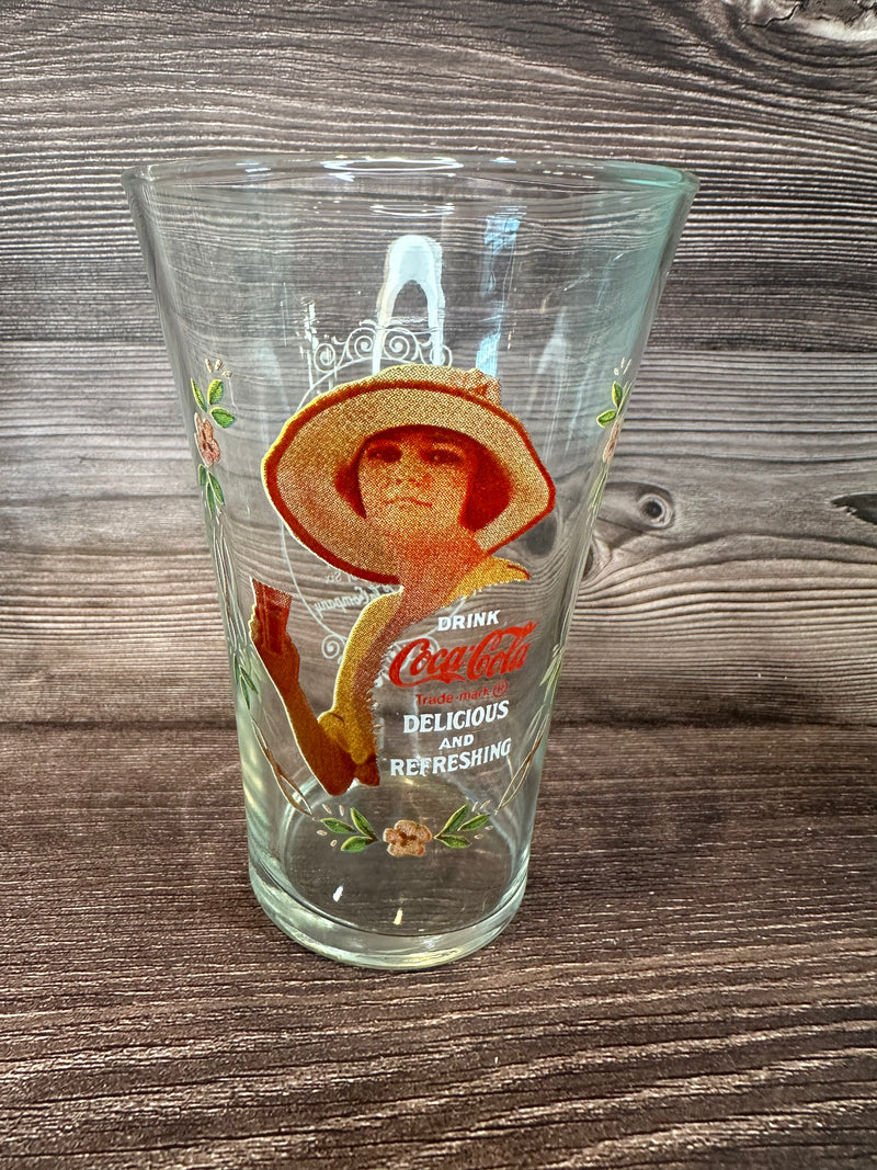 Vintage Coca Cola Magnificent Ladies Collector Series 1 Glasses featuring vibrant images of women in classic Coca-Cola advertising on a wooden surface.