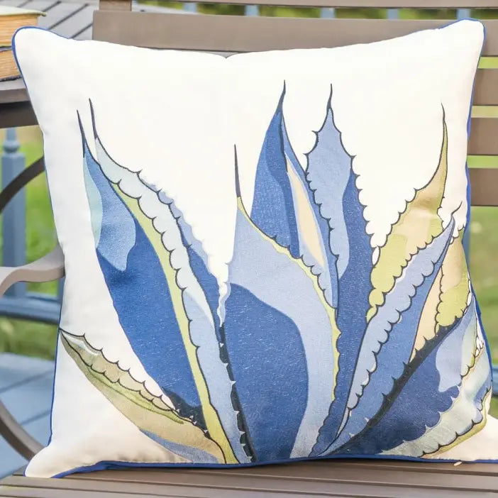 Agave-Tequila Maker Indoor/Outdoor Pillow with vibrant shades of blue agave design on a crisp white background, displayed on a patio chair.