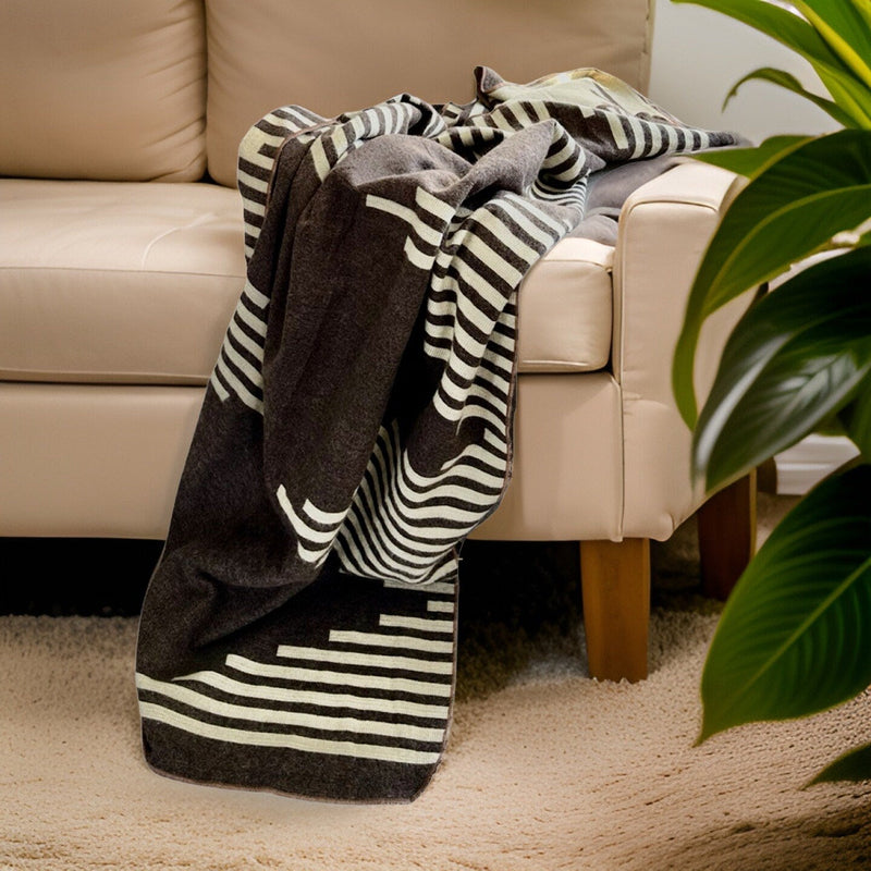 Coffee alpaca throw draped over a cream-colored armchair in a cozy living room setting.
