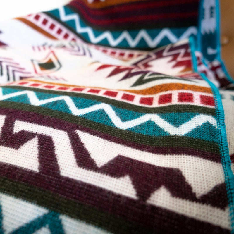 Close-up of turquoise Andean alpaca wool blanket showing vibrant geometric pattern and woven texture – artisanal coastal home décor accent