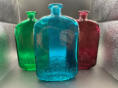 Photo of the Aqua, Green, and Magenta bottles under a light.