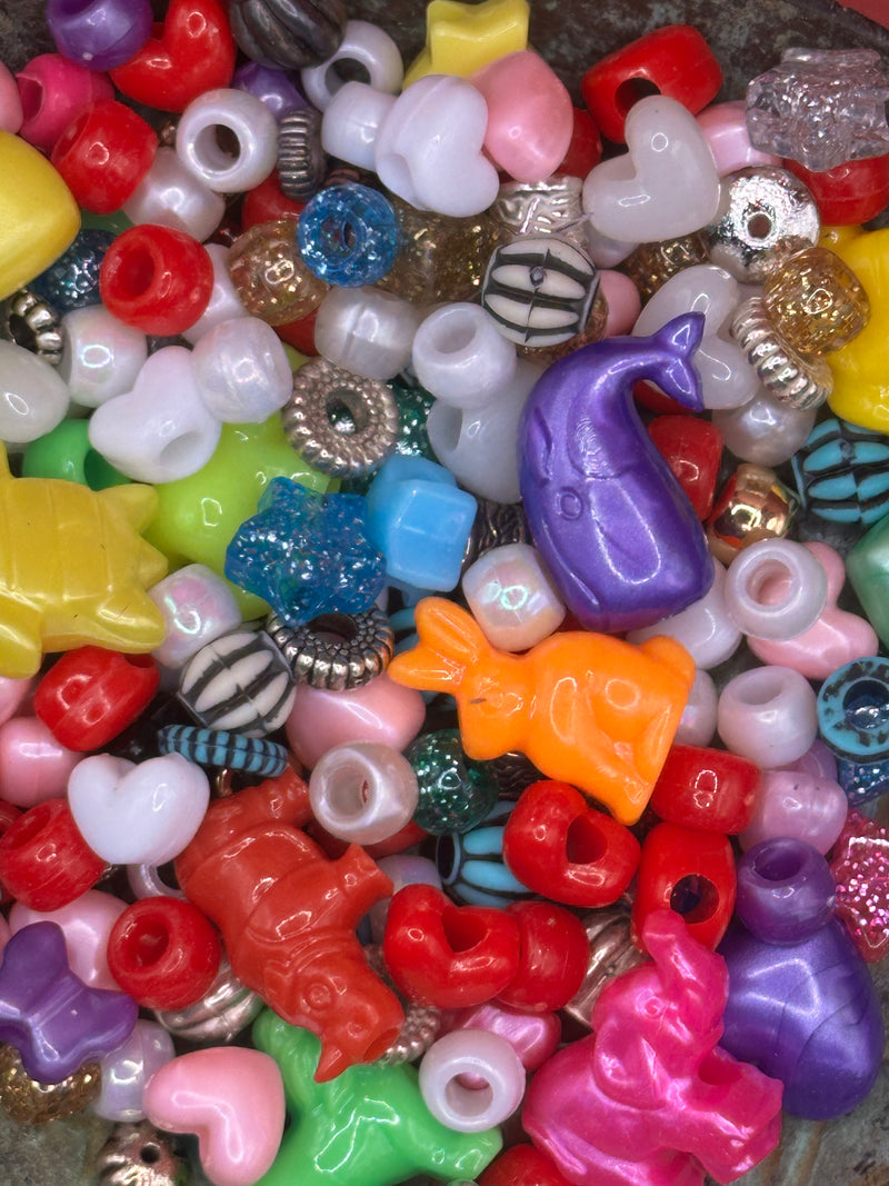 Assorted colorful beads including stars, hearts, and animals on a textured surface.