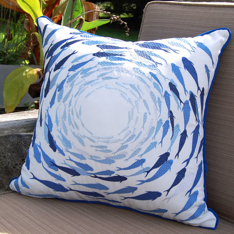 Angled view of the Azure Fish School Throw Pillow on a patio, highlighting the intricate embroidery and vibrant blue fish design.