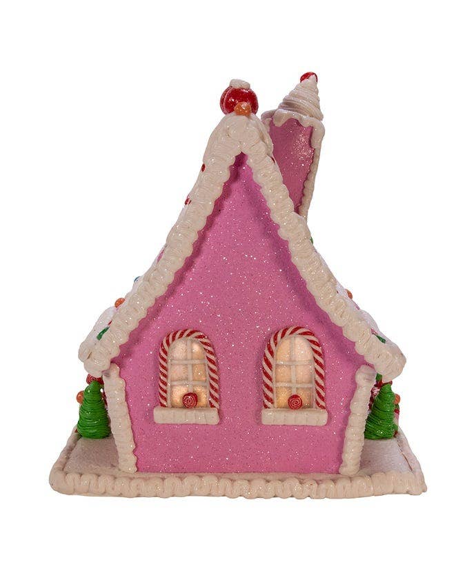 Pink gingerbread house with candy cane details on a white background