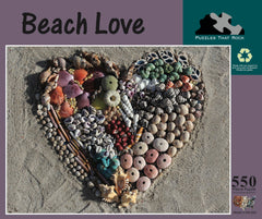 Beach Love 550-piece jigsaw puzzle box showing a heart-shaped design made of seashells and beach treasures.