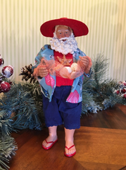 Beach Party Santa figurine surrounded by Christmas greenery and ornaments for festive coastal décor