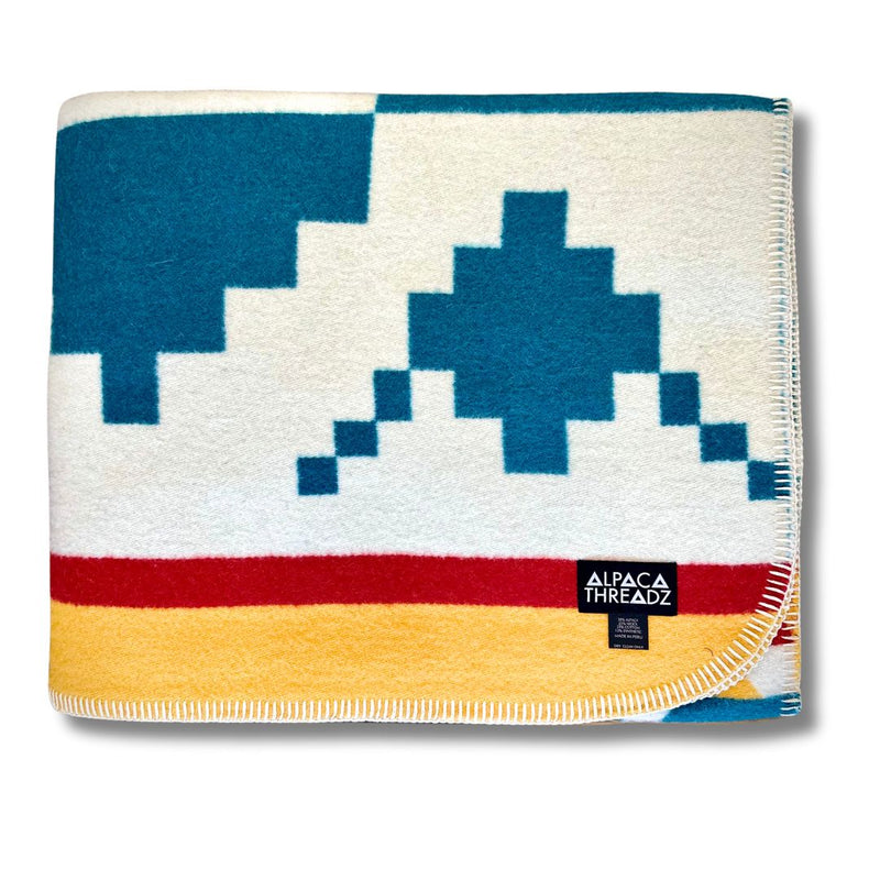 Folded corner view of the Blue/White/Yellow geometric alpaca blanket variant, showing blue and teal tones.