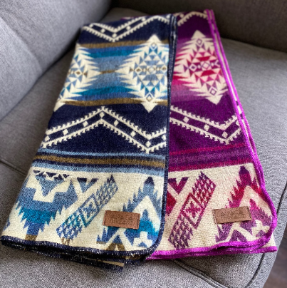 Two Alpaca Baby Blankets, Blue/Cream and Pink/Magenta, draped over a chair, comparing the bold colors and patterns.