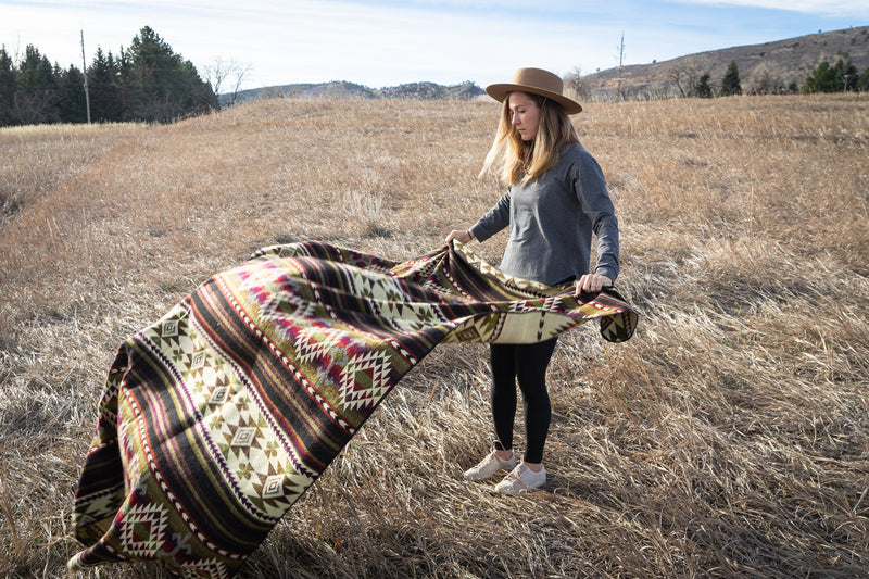 Cactus Alpaca Blanket held up in the wind, showing the fabric movement and the full pattern in a wide, empty field.