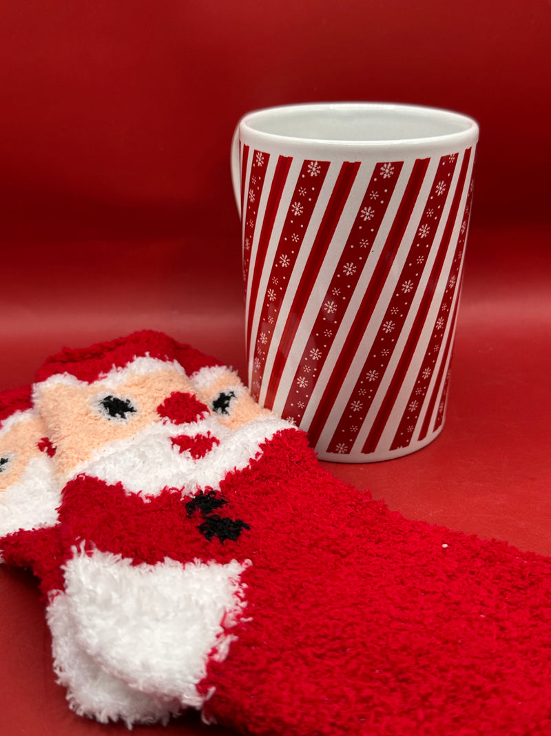Red and white striped candy cane mug shown with red fuzzy Christmas socks.
