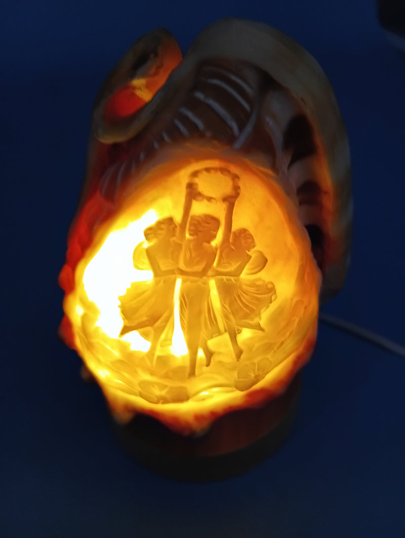 Carved cameo shell light glowing warmly with Three Graces design illuminated