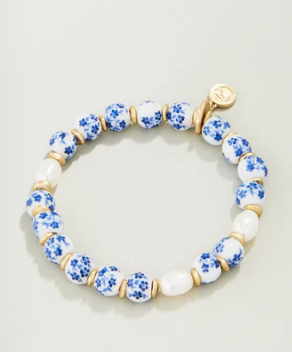 Bracelet with blue floral beads and gold accents on a light gray background