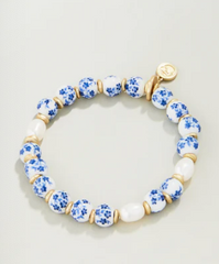 Bracelet with blue floral beads and gold accents on a light gray background