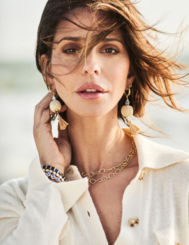 Woman wearing gold earrings and a necklace with a blurred background