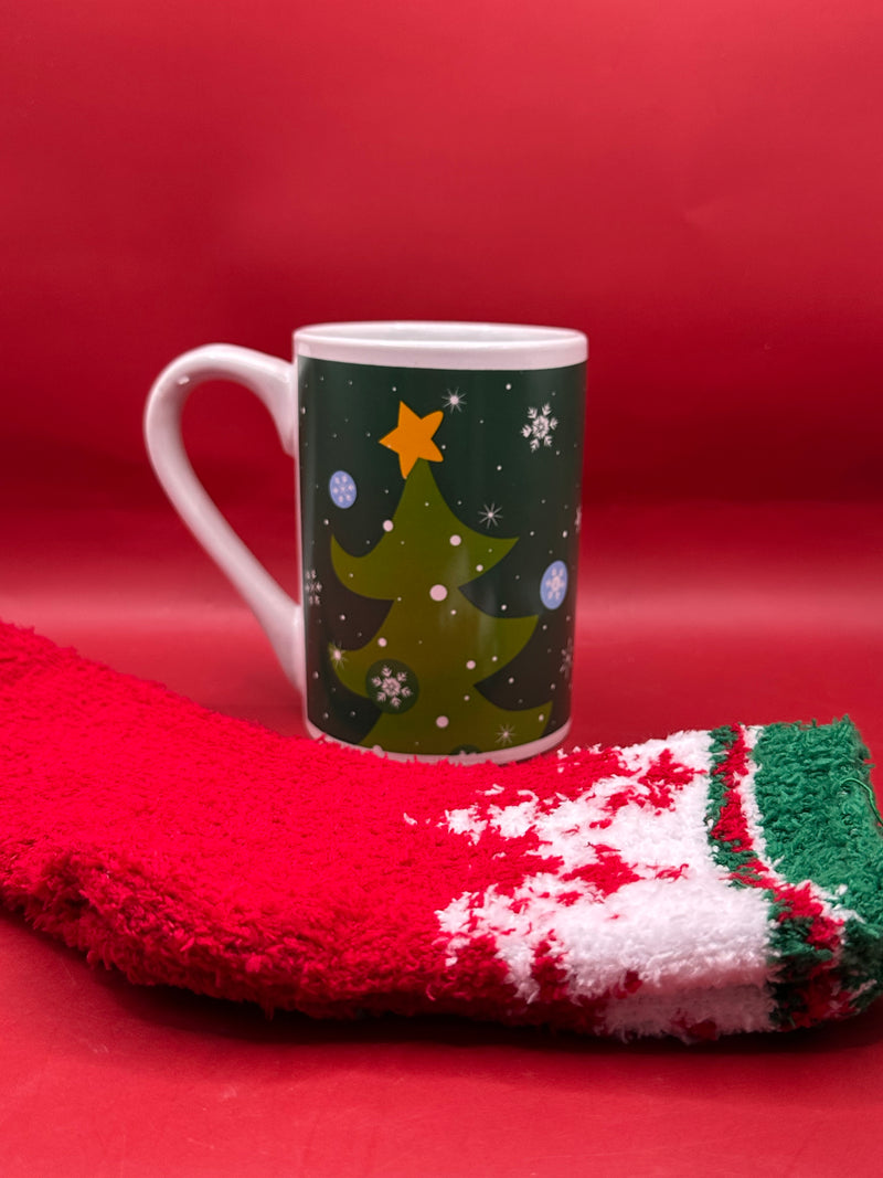 Dark green mug decorated with Christmas trees and gold stars, paired with fuzzy socks.