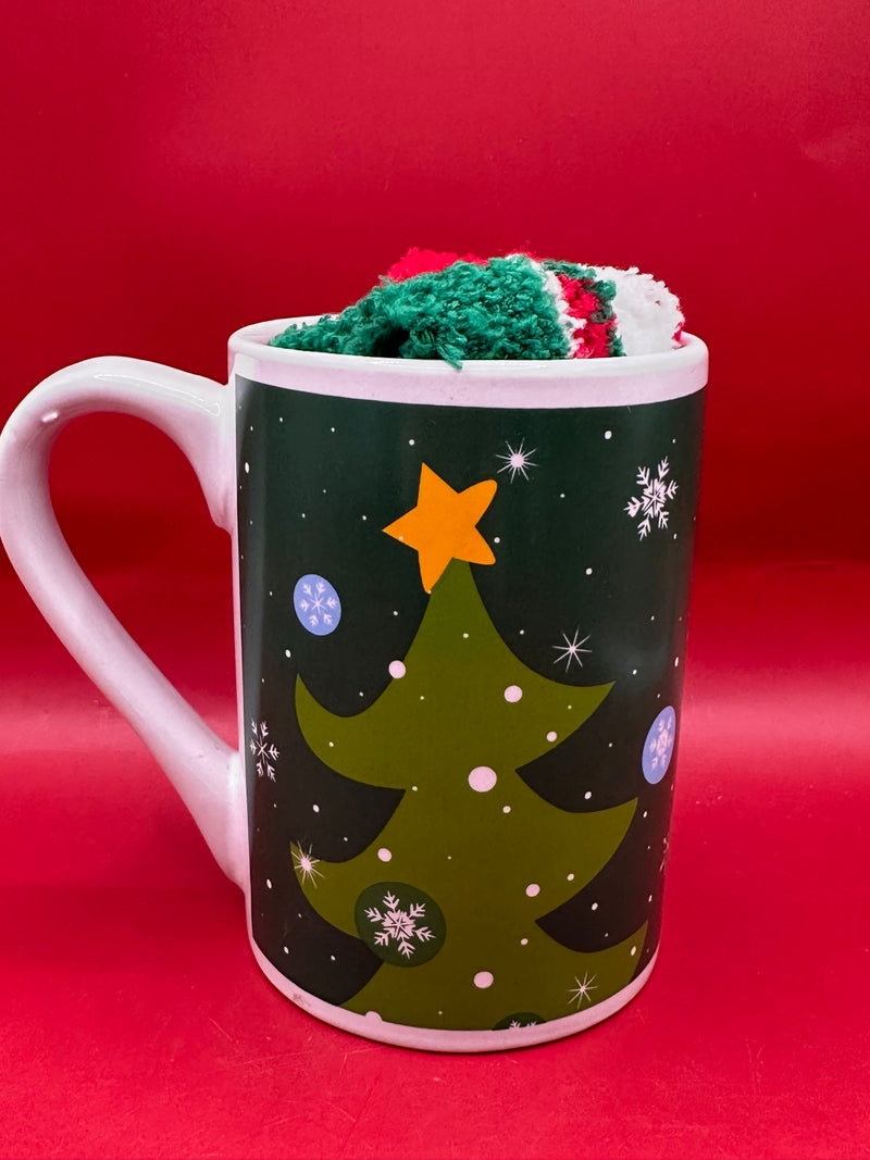 Dark green mug decorated with Christmas trees and gold stars, paired with fuzzy socks.