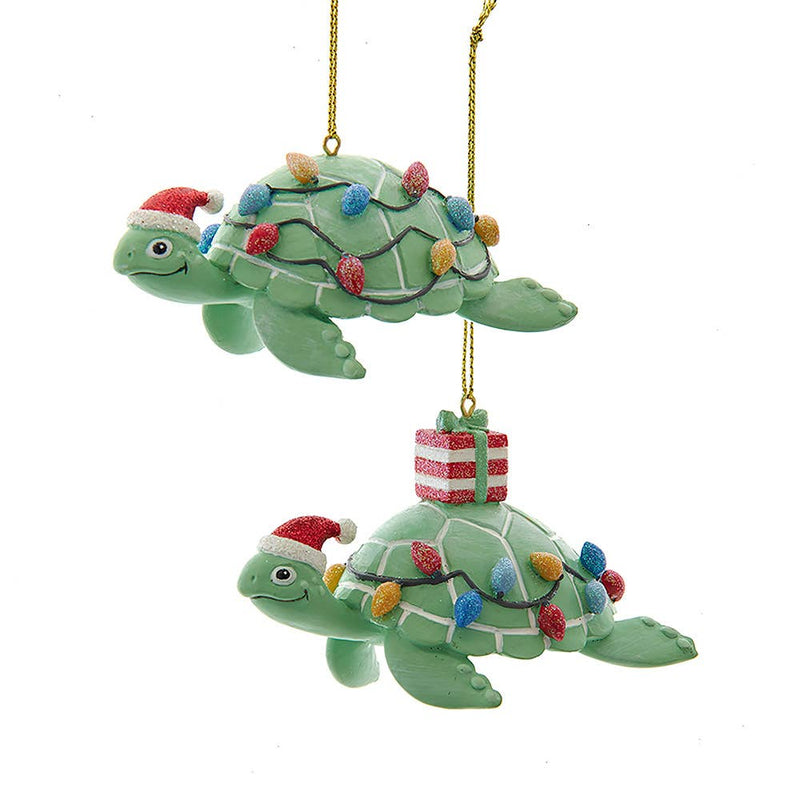Two green turtle Christmas ornaments with lights and a gift on a white background