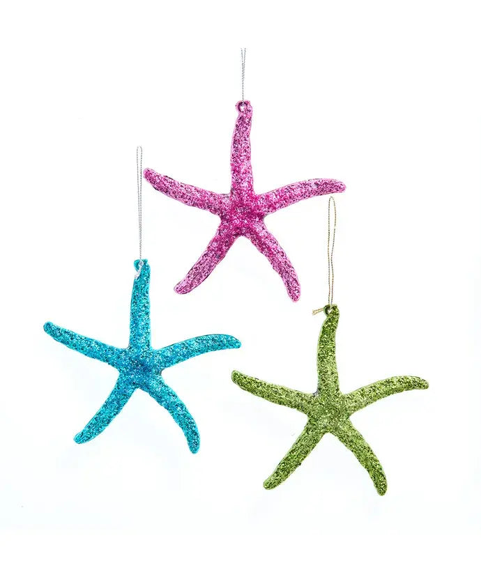 Three glittery starfish ornaments in pink, blue, and green on a white background.
