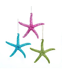 Three glittery starfish ornaments in pink, blue, and green on a white background.