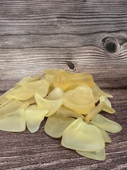 A pile of citrus colored sea glass on a wooden background.