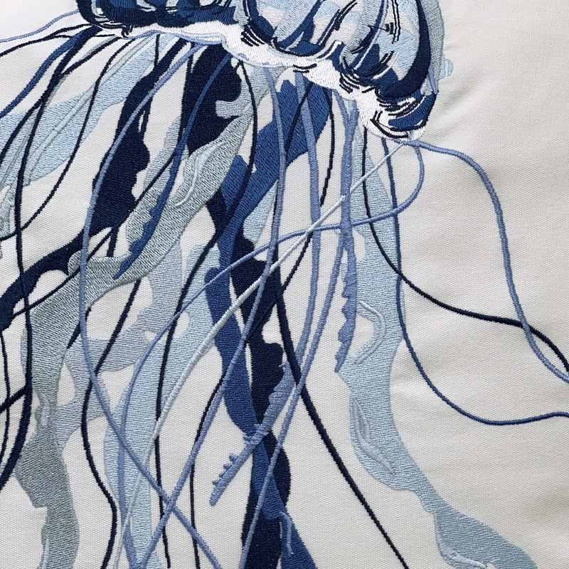 Close-up of the embroidered jellyfish design on the pillow, capturing the intricate details of the blue threadwork.