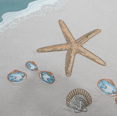 Close-up of the embroidered starfish and shell details on the Sand & Shells Table Runner, highlighting its intricate craftsmanship.