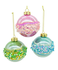 Three colorful glass ornaments with floral and glitter designs on a white background