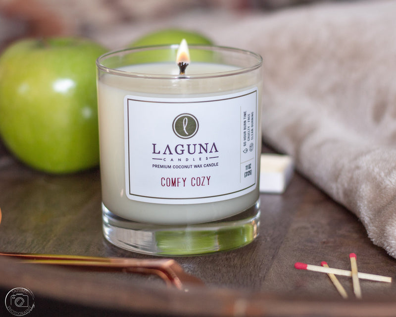 Laguna candles 'Comfy Cozy' candle with green apples and matches on a wooden surface