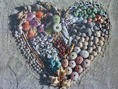 Completed Beach Love puzzle featuring a heart-shaped arrangement of seashells and treasures on a sandy background.