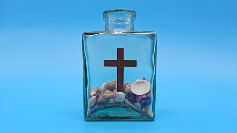 Christian decorative bottle with cross emblem and ocean shells – spiritual gift idea