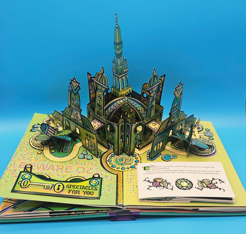 An angled view of the large Emerald City pop-up structure in the book, highlighting the green details and 3D layers against a blue background.