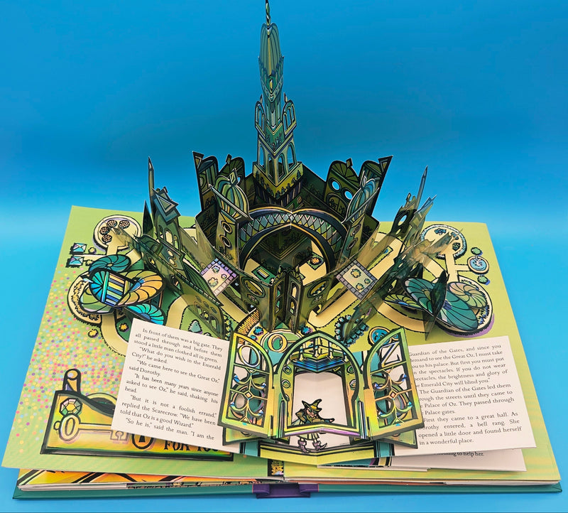 The Emerald City pop-up scene in the Wizard of Oz book, showcasing the elaborate green 3D paper structure when the book is fully open.