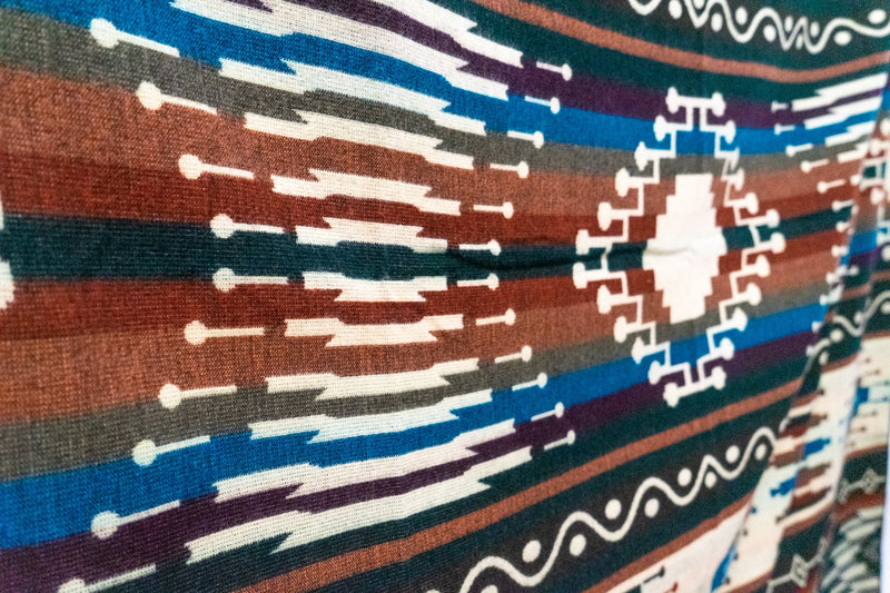 Tight close-up of the Evergreen blanket pattern, focusing on the interwoven teal, rust, and white geometric lines.