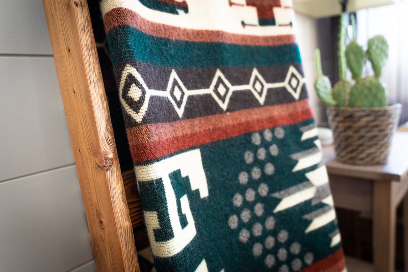 Close-up detail of the Evergreen blanket on the ladder, highlighting the dark teal/green and burgundy pattern blocks.