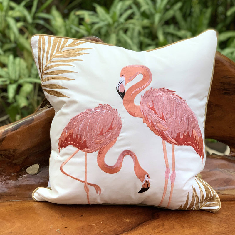 Flamingo Fancy Embroidered Indoor/Outdoor Pillow featuring bold flamingos with gold and silver threads, displayed on a wooden bench.