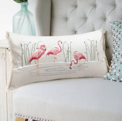 Flamboyance Lumbar Pillow displayed on a chair, showcasing its playful flamingo embroidery and elegant fringed design.