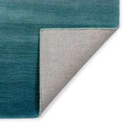 A folded corner of the luxurious blue ombre indoor rug measuring 5'x7'6