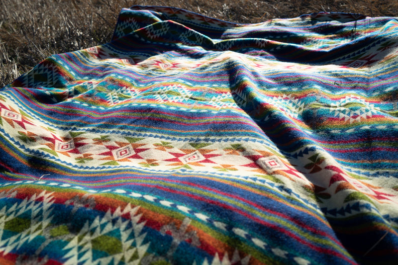 Extreme close-up of the Galapagos Blanket's folded edge and texture against the dry grass backdrop.