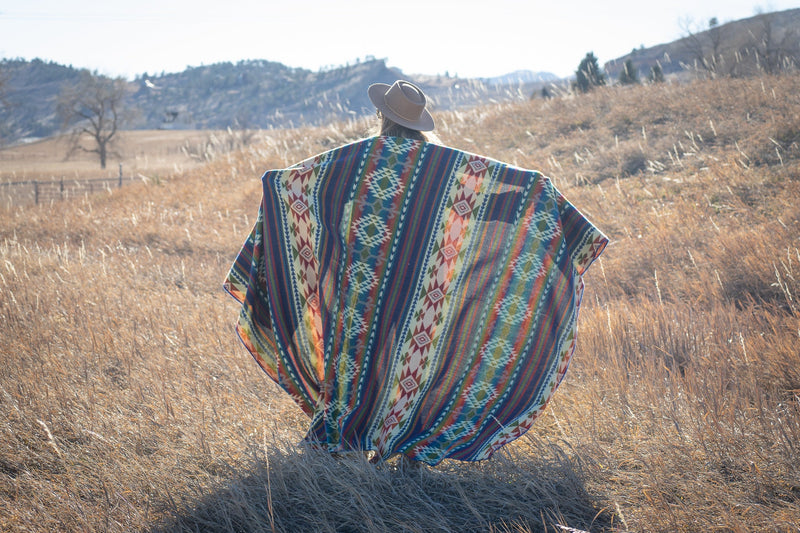 Woman holding the Galapagos Blanket loosely draped over her arms, showing the scale and colors in the sunshine.
