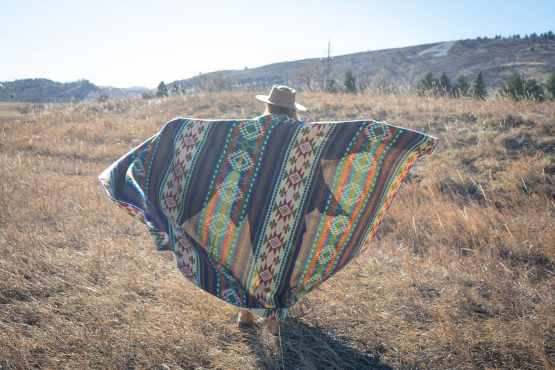 Woman holding the Galapagos Blanket draped over one side, highlighting the deep navy and maroon color bands.