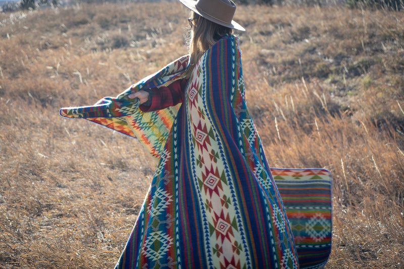 Woman wrapped in the Galapagos Blanket, seen from a side profile against the clear blue sky.