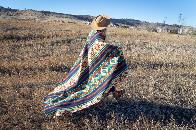Woman wrapped and moving with the Galapagos Blanket in the field, emphasizing its large size and flowing material.